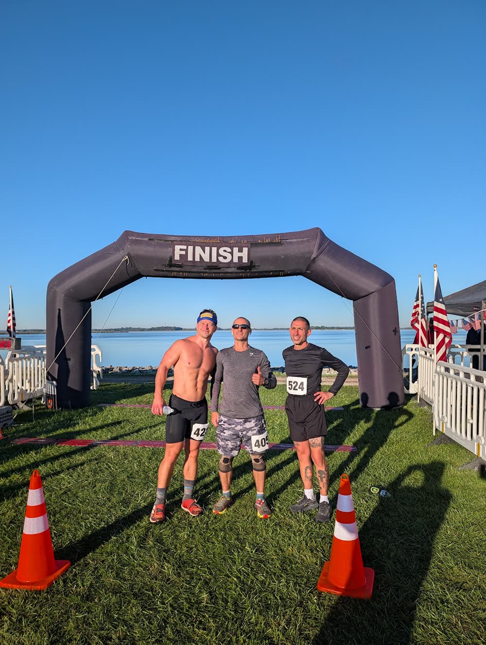 Three runners standing together beneath the finish arch beside Findlay Reservoir during the 2026 race